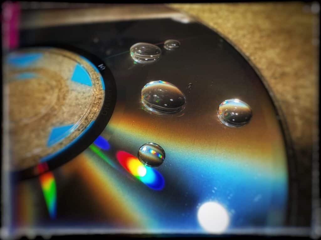 Drops of water on a CD disk with bright abstract lighting and coloring
