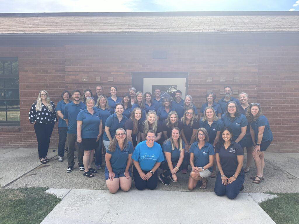 Staff picture with teacher standing infront of the LaunchED Campus building.