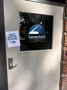 First day of school sign posted on a door with the school logo