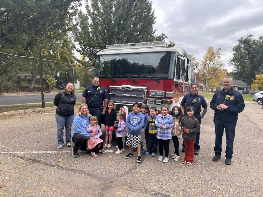 Students standing around the firetruck with both firefighters and their teachers