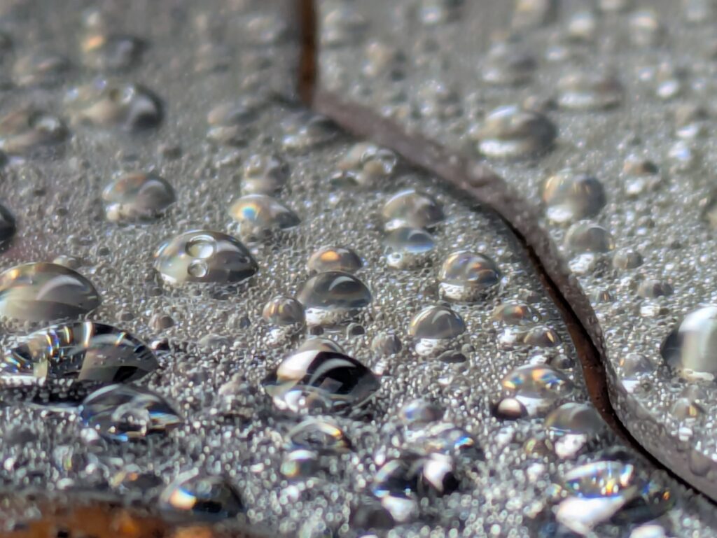 Close-up of water droplets on a textured surface, reflecting light and creating a shimmering effect.